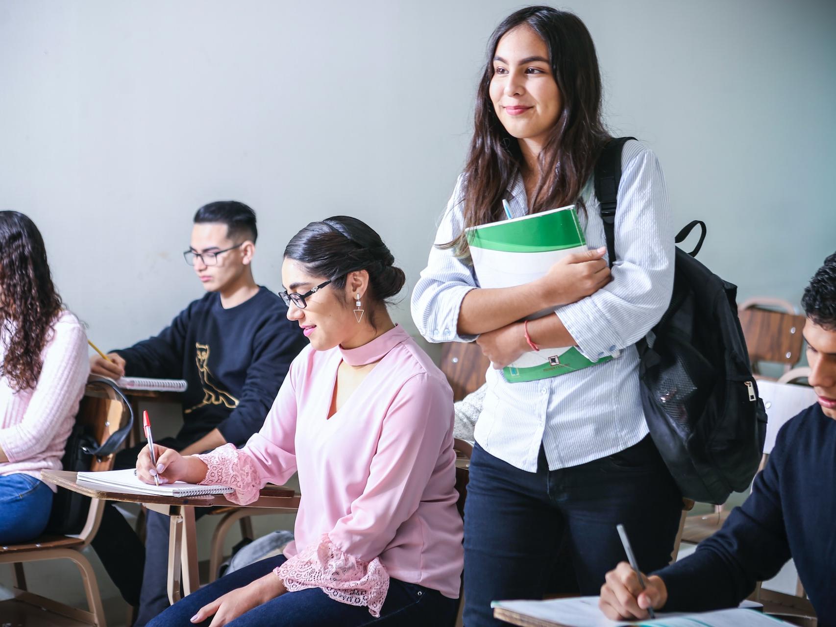 woman carrying white and green textbook